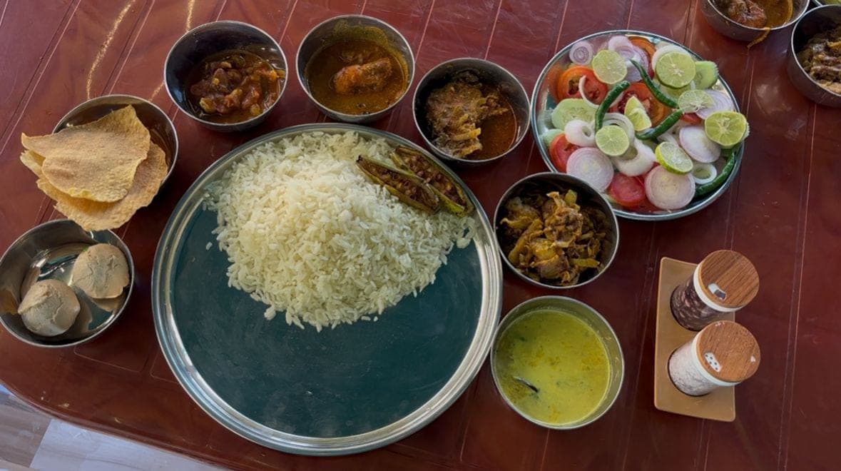 A rice thali with vegetable sides, salad, and papad