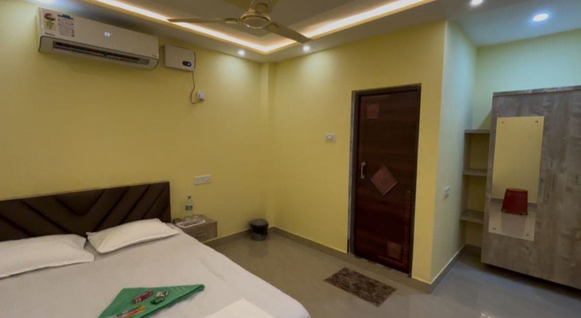 One-bed room with yellow walls, a made bed, and an air-conditioner