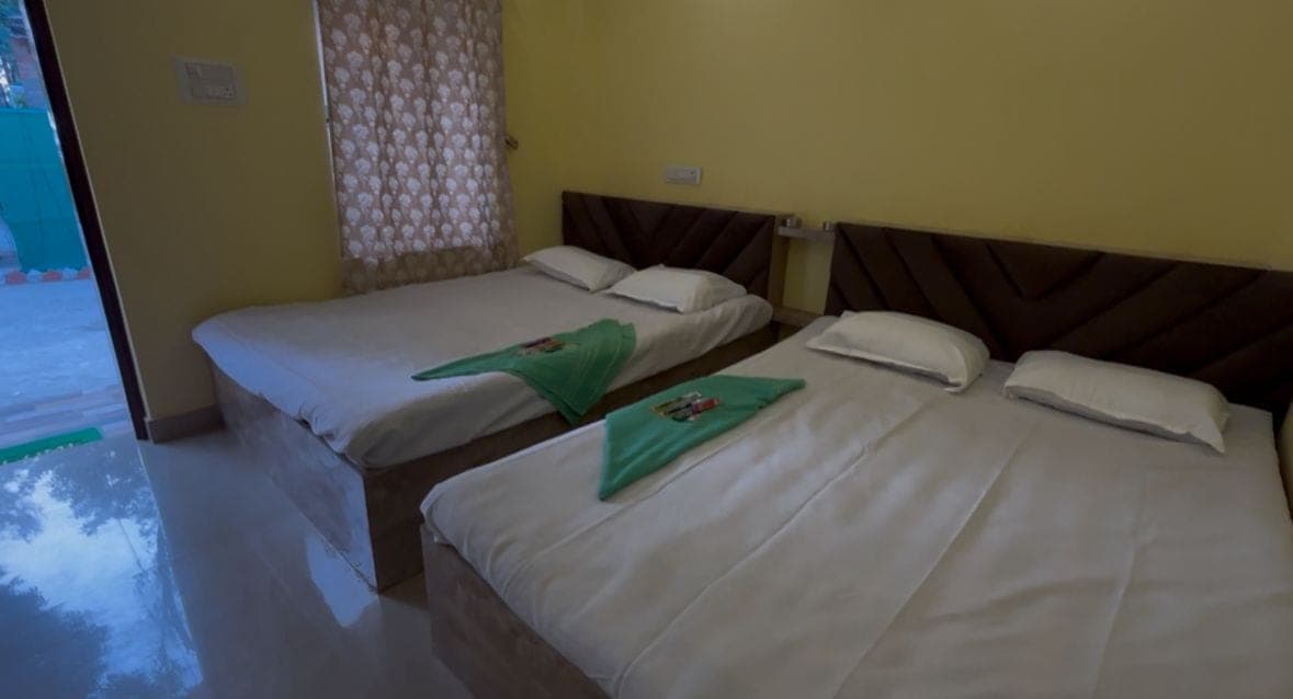 Two-bed room with two made beds and a doorway to the outside